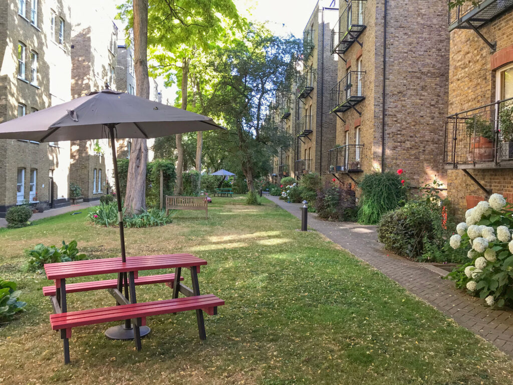 A view of a seating area in the communal gardens at the rear of Morshead Mansions in summer