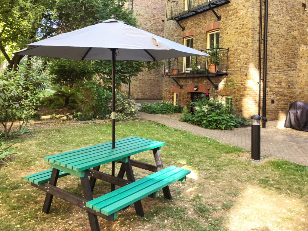 A view of a seating area in the communal gardens at the rear of Morshead Mansions in summer